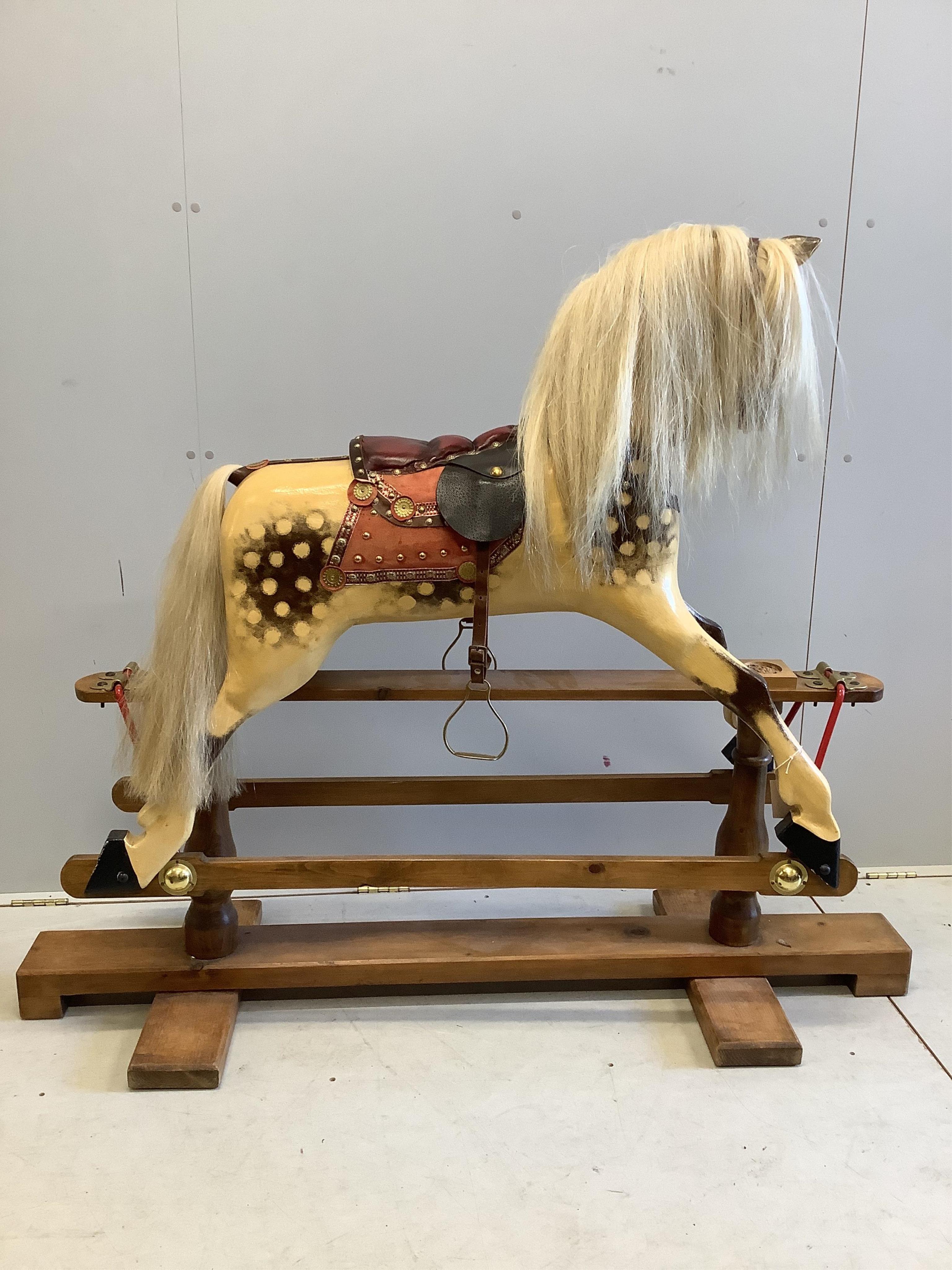 A large carved wooden rocking horse on a pine stand, the body painted in dapple grey, with glass eyes and upholstered leather saddle, height to the top of the head 130cm, length of base 152cm. Condition - fair to good.
